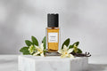 YSL Tuxedo decant bottle surrounded by flowers and vanilla pods on marble background.